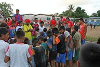 Children crowd around to watch a game of marbles.